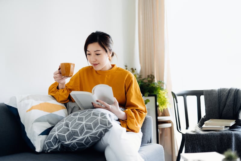 Beautiful-young-Asian-woman-reading-a-book-while-drinking-a-cup-of-coffee-how-to-focus-on-yourself