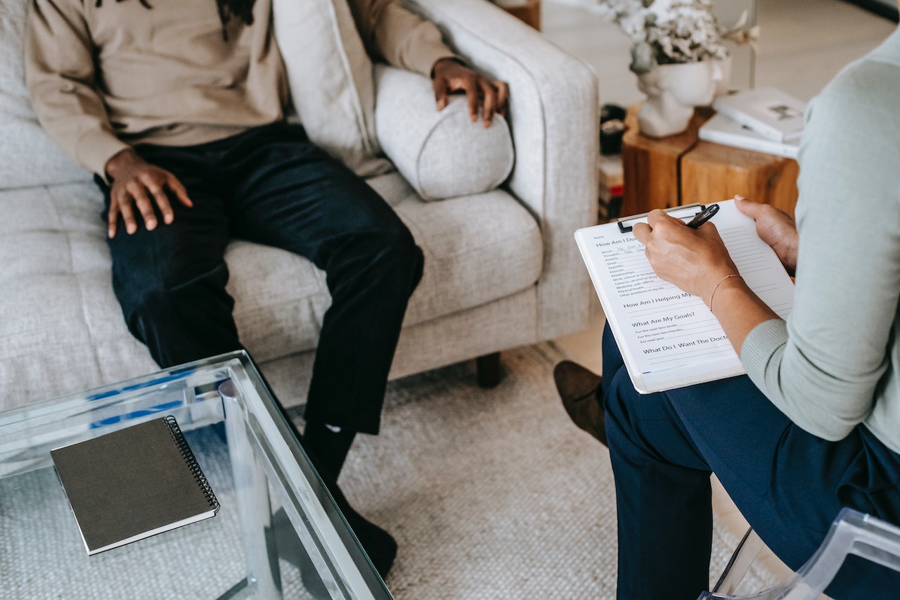 Close-up-of-life-coach-writing-down-in-notes-with-her-patient-psychology-degree-jobs
