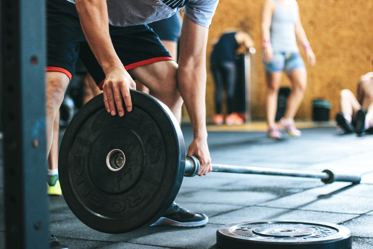 Close-up-of-mans-hands-setting-up-weights-on-bar-at-the-gym-unique-employee-benefits