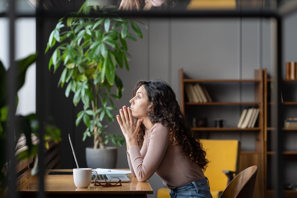 Female-thinking-in-front-of-laptop-how-to-overcome-lack-of-ambition