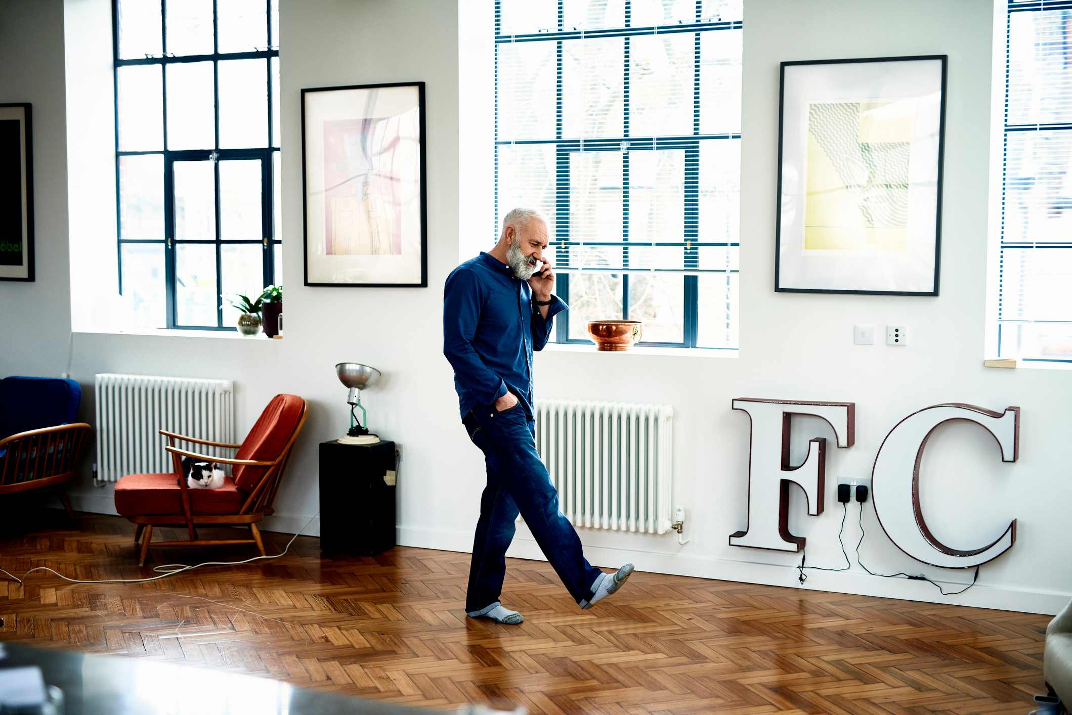 Hipster-senior-man-on-cell-phone-in-funky-apartment-purpose-of-anger-emotion