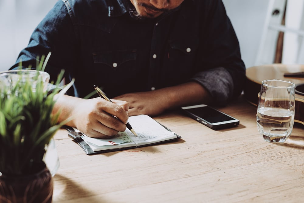 Male-writing-notes-in-a-desk-linkedin-profile