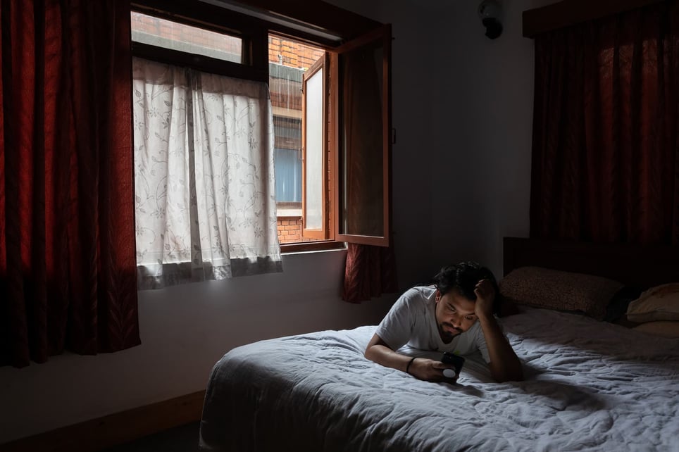 Man-alone-in-room-looking-at-his-phone-1