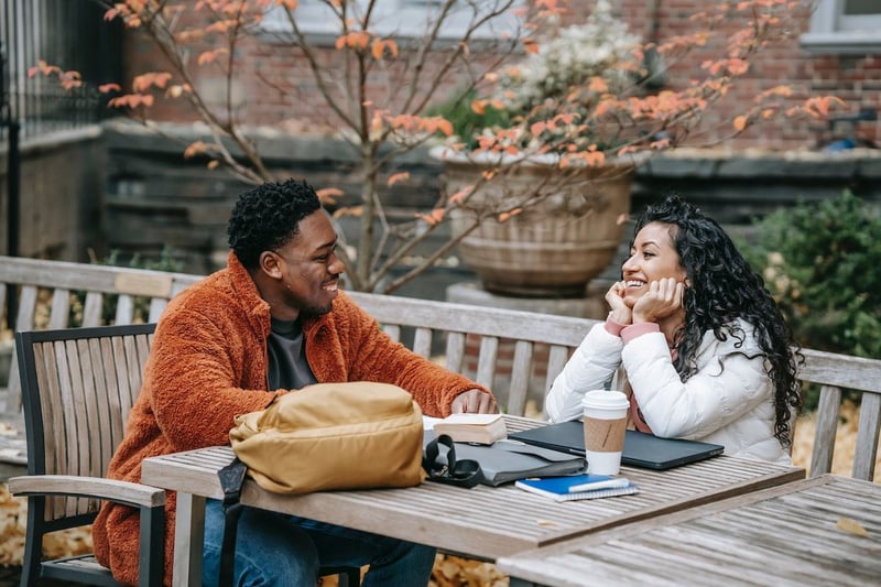 Man-and-woman-talking-and-laughing-at-table-outdoors-deep-questions-to-ask