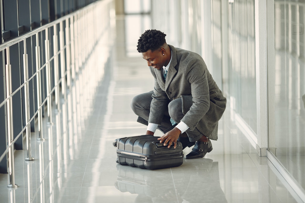 Man-at-airport-hallway-closing-his-carry-on-suitcase-stipend-vs-salary