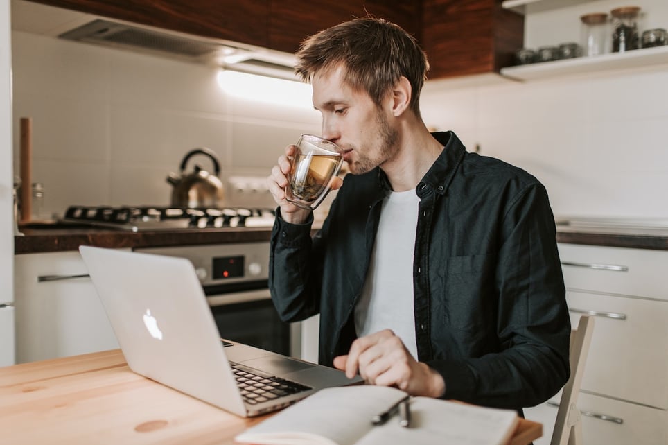 Man-drinking-his-tea-while-doing-research-in-his-laptop-at-kitchen-stipend-vs-salary