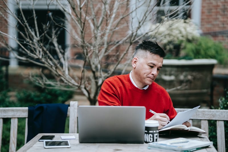 Man-workinf-from-home-writing-on-notebook-how-to-send-a-reminder-email