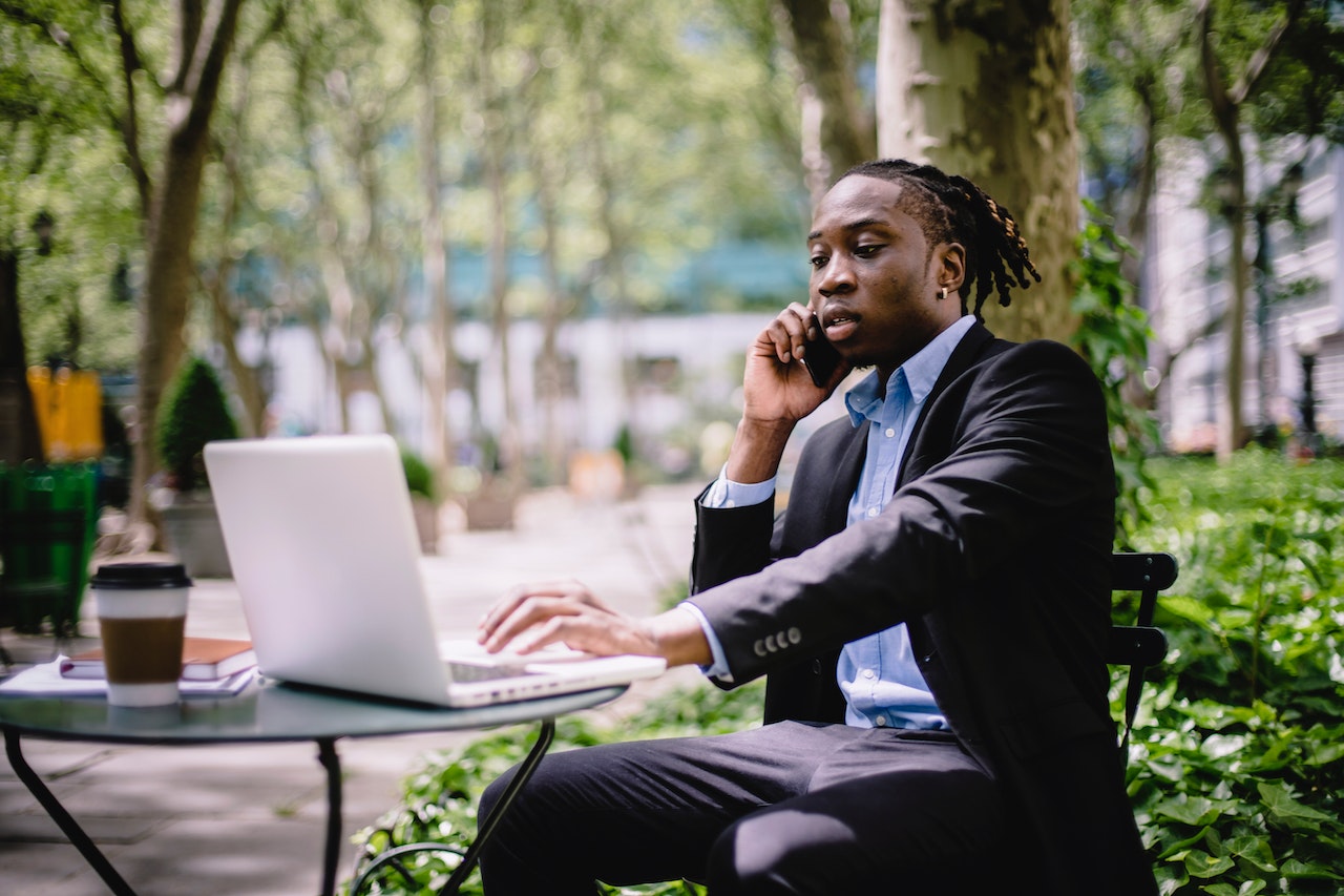 Man-working-on-coffee-shop-outdoors-while-talking-on-the-phone-salary-negotiation-tips