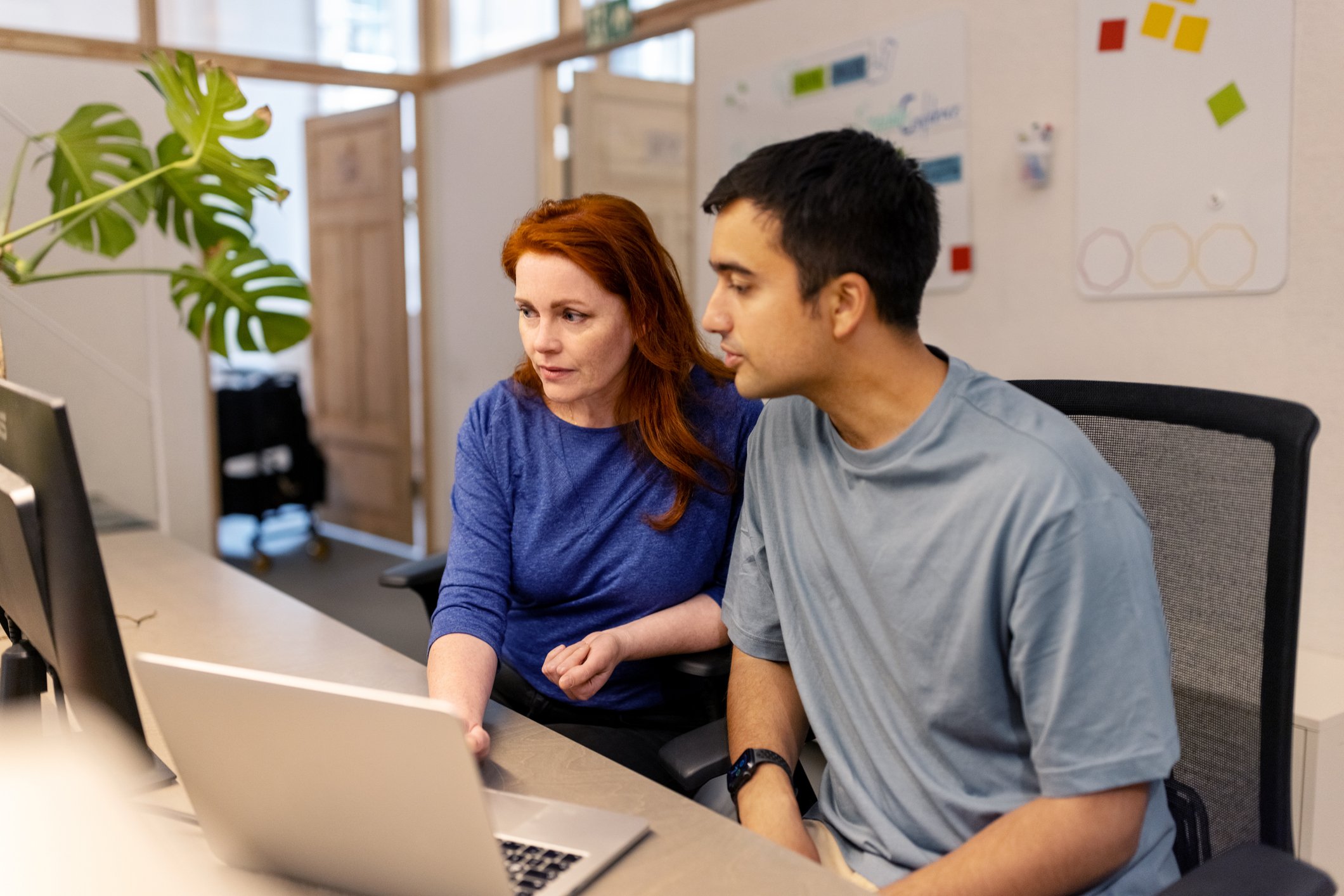 Manager-showing-in-computer-something-to-her-employee-workplace-environments