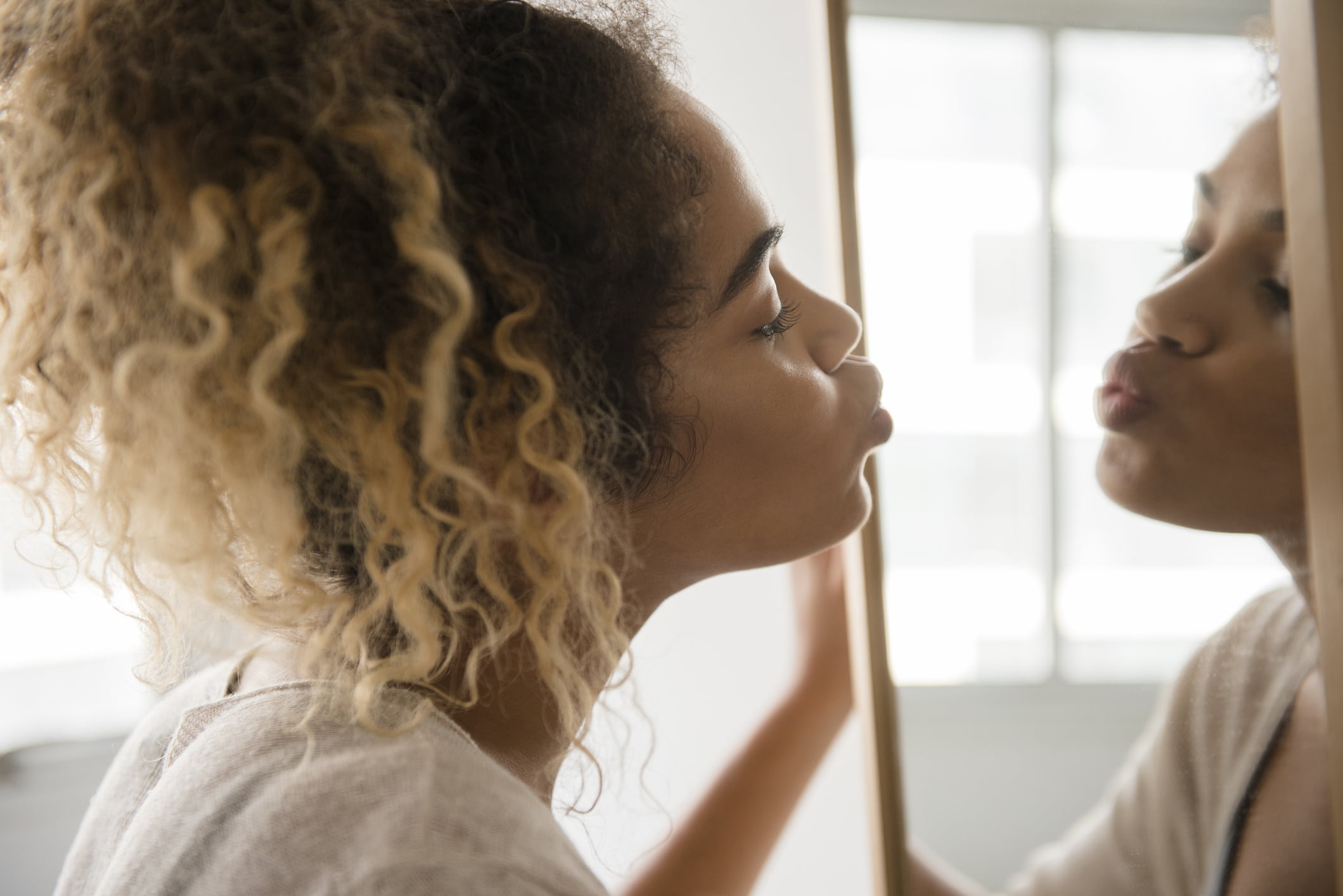 Mixed-Race-woman-puckering-lips-in-mirror-benefits-of-knowing-yourself