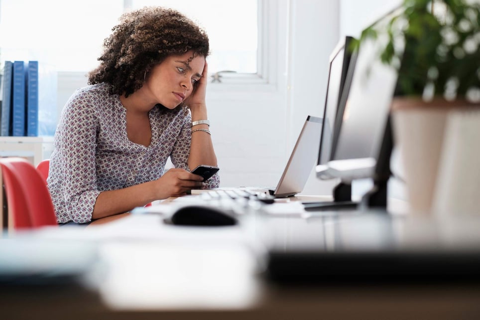 Stressed-woman-looking-at-her-cellphone-at-office-why-is-there-a-labor-shortage