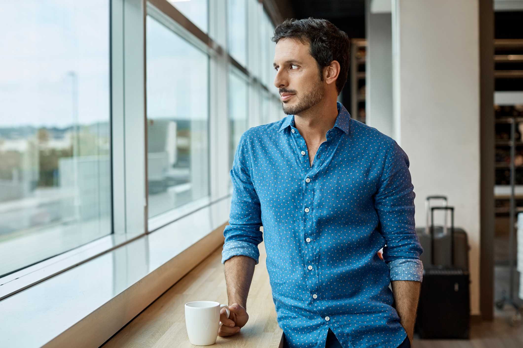 Thoughtful-man-with-coffee-cup-looking-outside-the-window-affirmations-for-imposter-syndrome