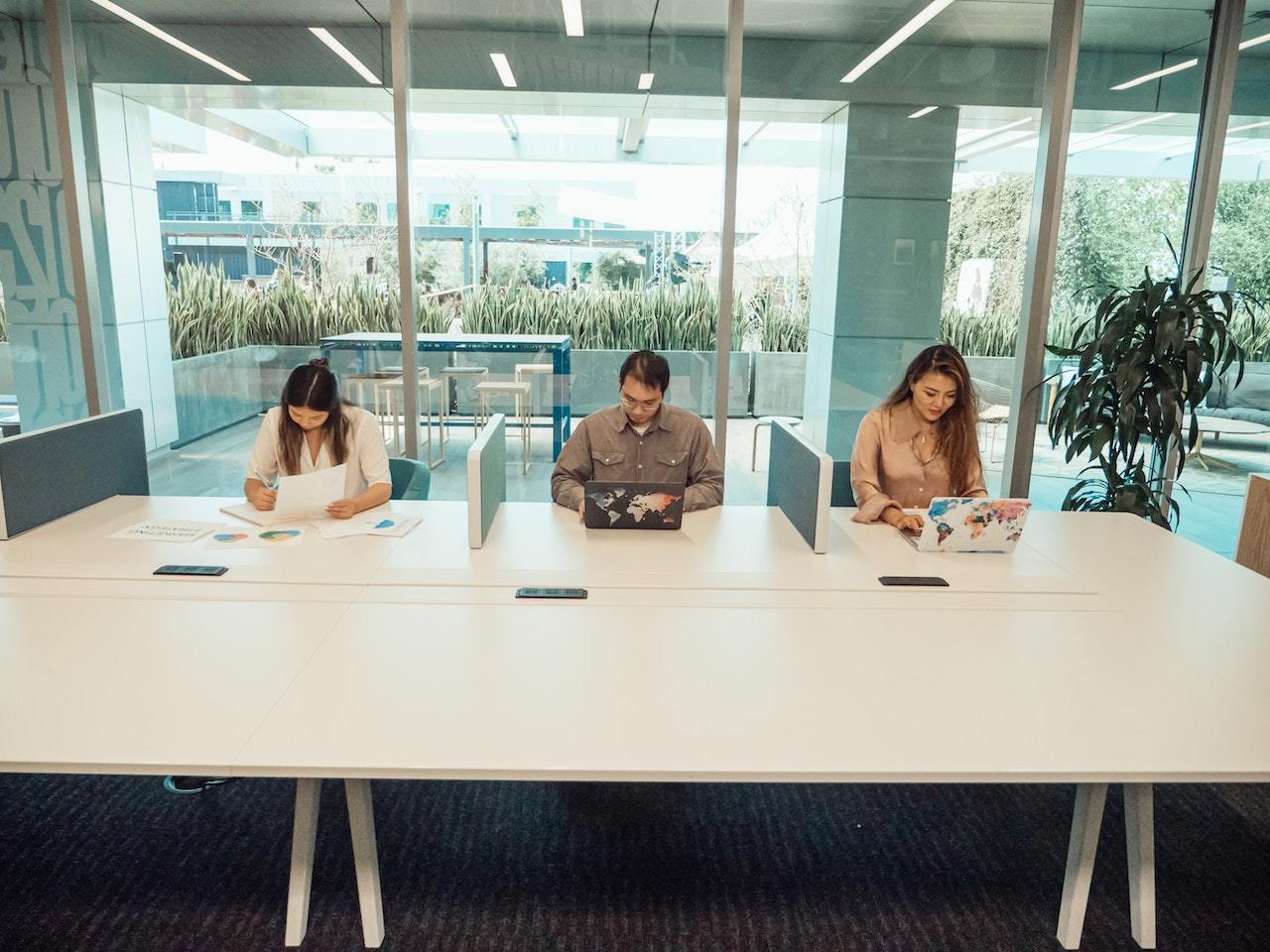 Three-people-in-coworking-space-working-on-their-laptops-unique-employee-benefits