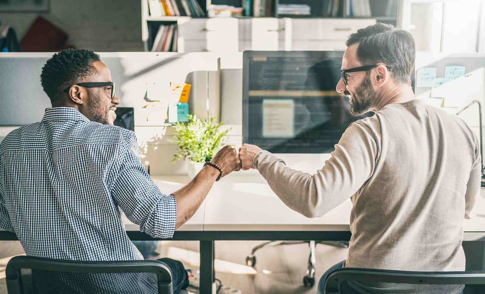 Two-coworkers-giving-high-five-at-office-how-to-help-someone-with-imposter-syndrome