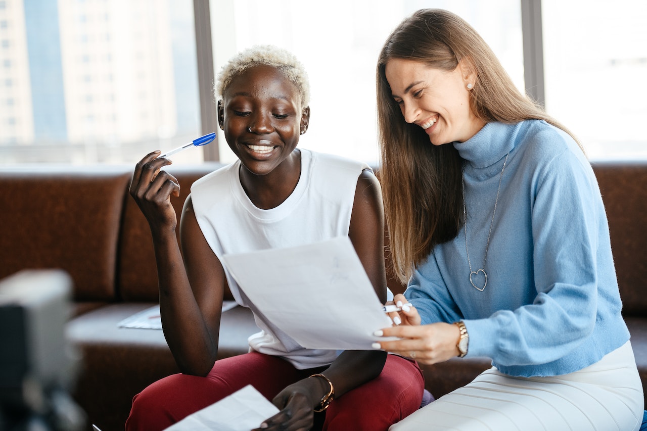 Two-young-coworkers-laughing-at-office-stipend-vs-salary