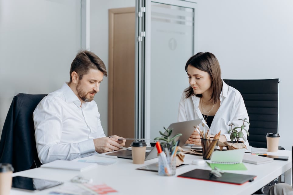 Woman-talking-to-her-manager-on-his-office-looking-at-documents-salary-negotiation-tips