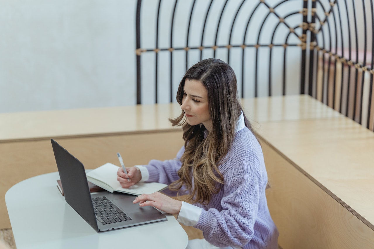 Woman-writing-on-laptop-while-sitting-at-home-how-to-message-a-recruiter-on-LinkedIn