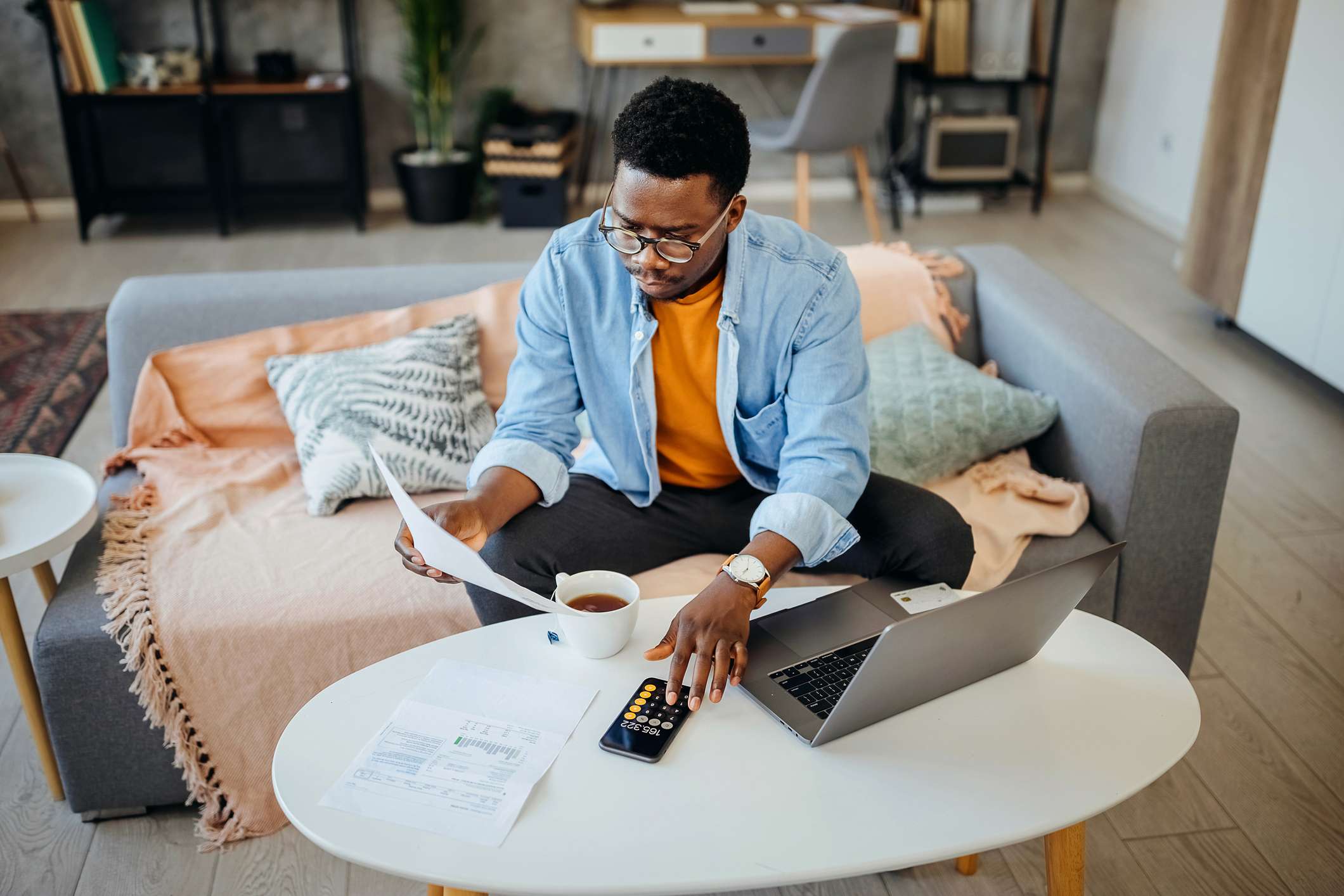 Young-man-looking-at-bills-and-using-calculator-how-to-choose-my-own-life-path-as-a-millennial