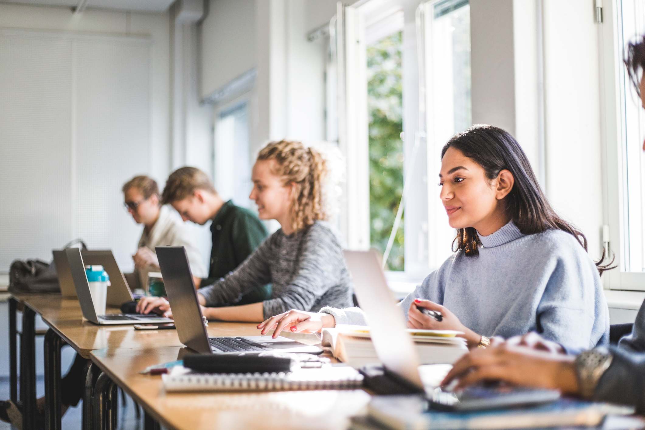 Young-woman-with-laptop-at-college-classroom-part-time-employee-benefits