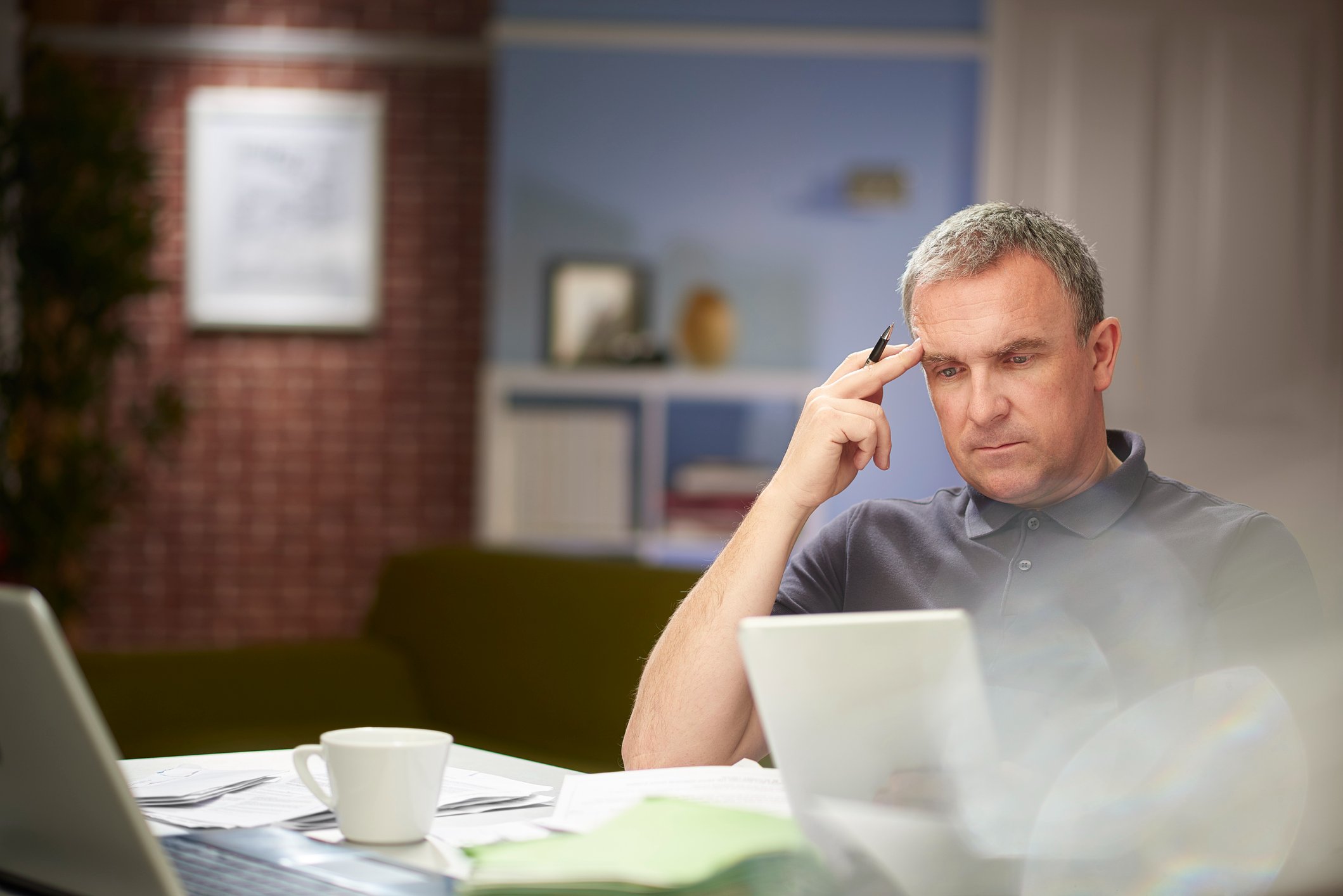 a-mature-man-sits-at-his-dining-table-at-home-looking-through-some-bills-how-to-decide-between-current-job-and-new-job