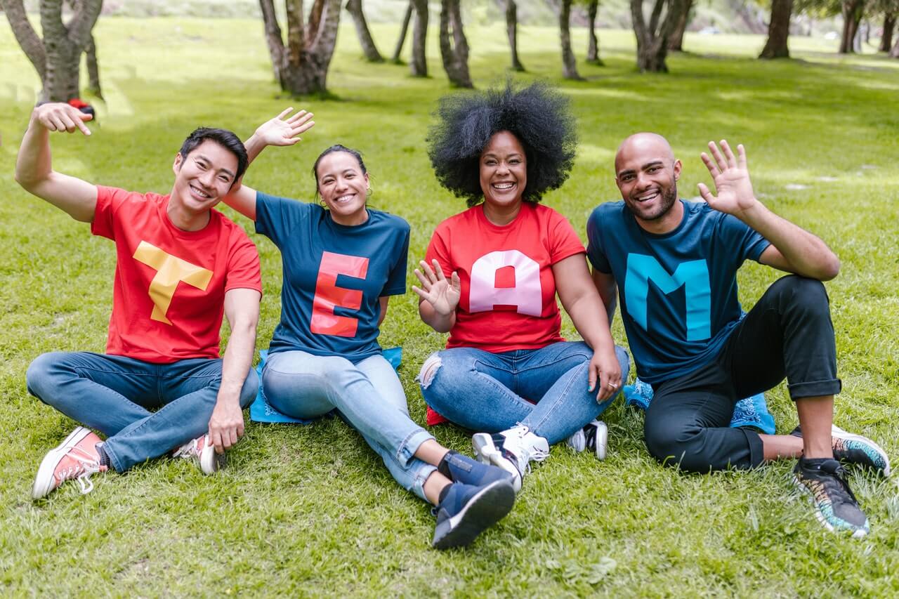 diverse-team-sitting-on-grass-smiling-and-waving-what-is-altruism
