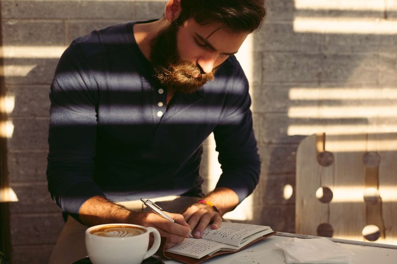 man-with-a-beard-writes-in-his-journal-how-to-challenge-yourself