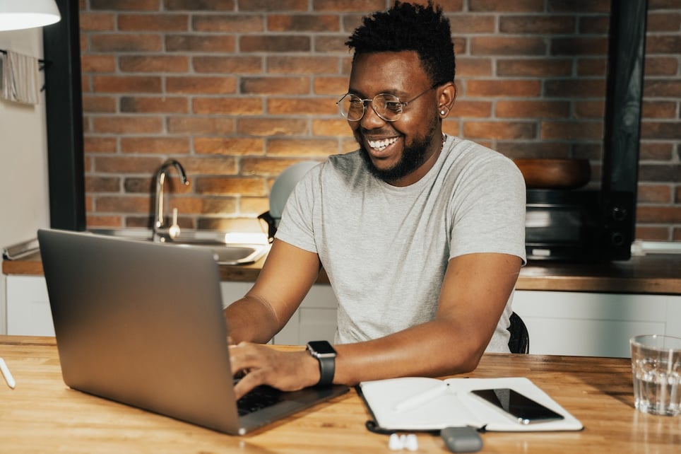 man-writing-on-laptop-at-home-smiling-how-to-message-a-recruiter-on-LinkedIn