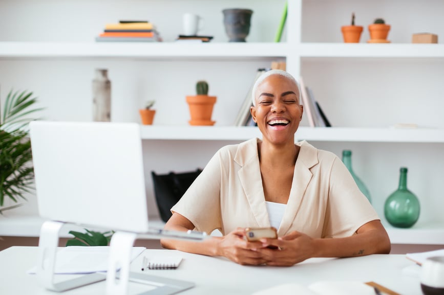 woman-holding-a-mobile-phone-having-a-laugh-while-working-in-office-how-to-focus-better