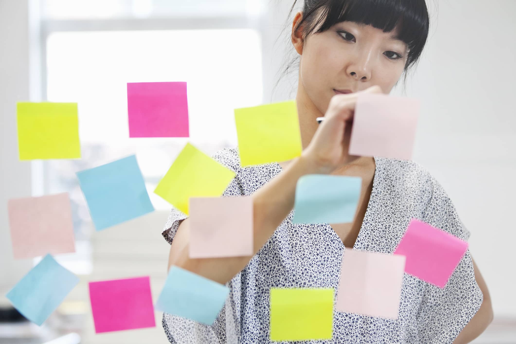 woman-writing-on-sticky-notes-purpose-vs-mission-vision