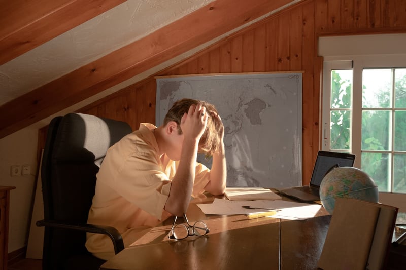 young-male-on-his-desk-with-hands-on-his-head-1