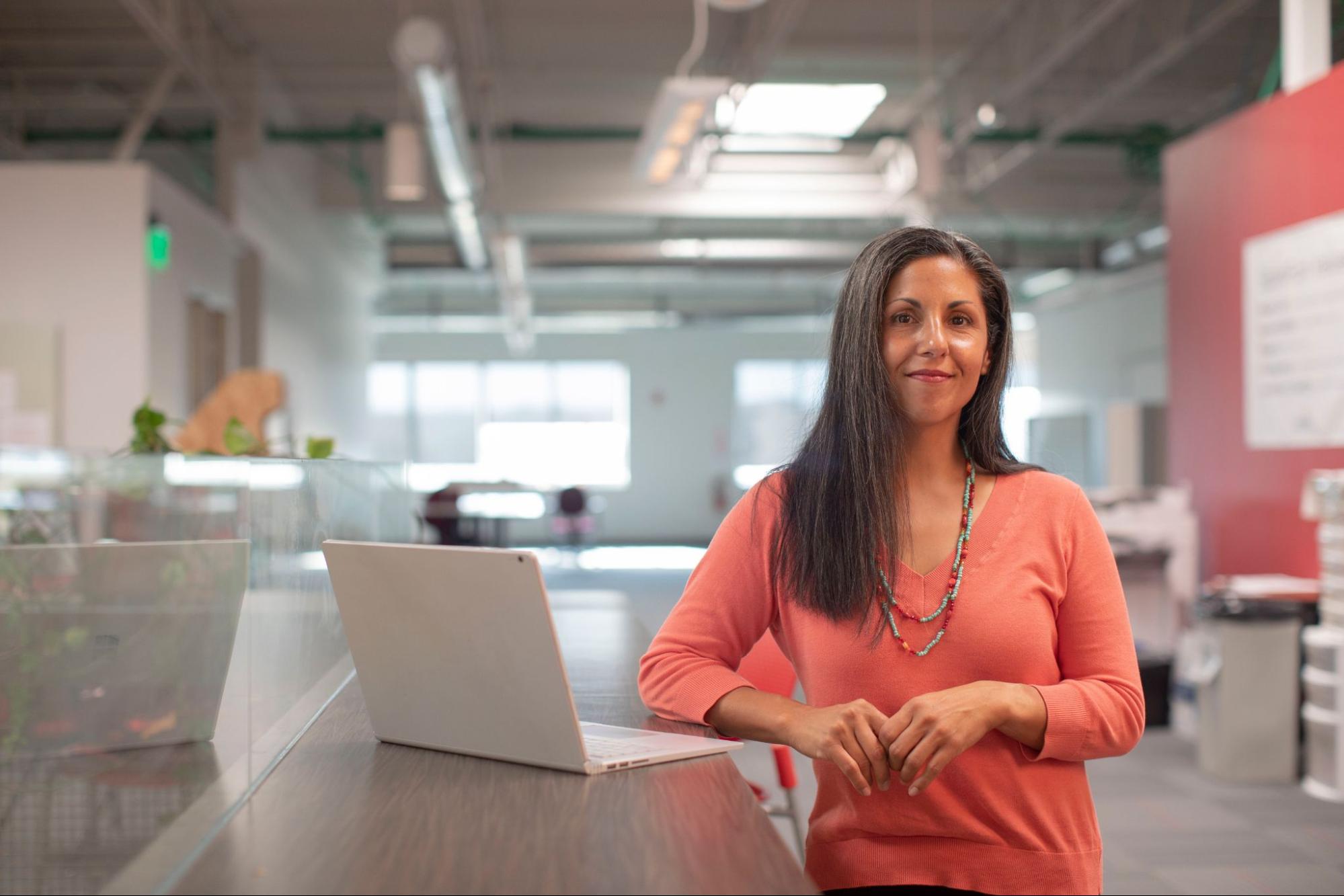 woman-standing-next-to-laptop-looking-forward-executive-development